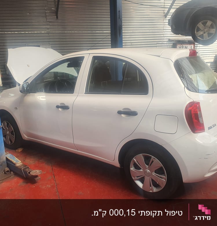 רכב לבן במוסך עם מכסה מנוע פתוח